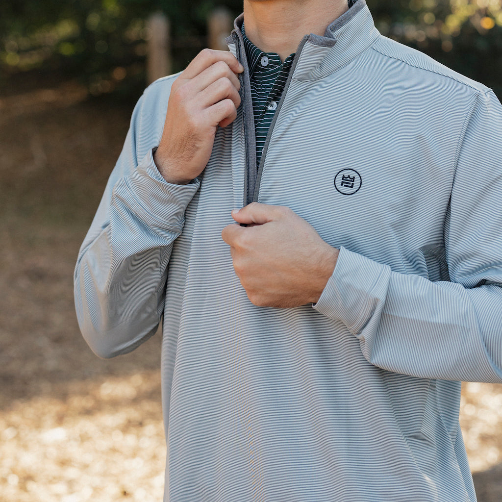 The Grey Quarter Zip outerwear piece features a subtle stripe pattern that flatters all and pairs with your favorite golf polo. It's breathability and stretch properties provide optimal mobility from the office to a night out.