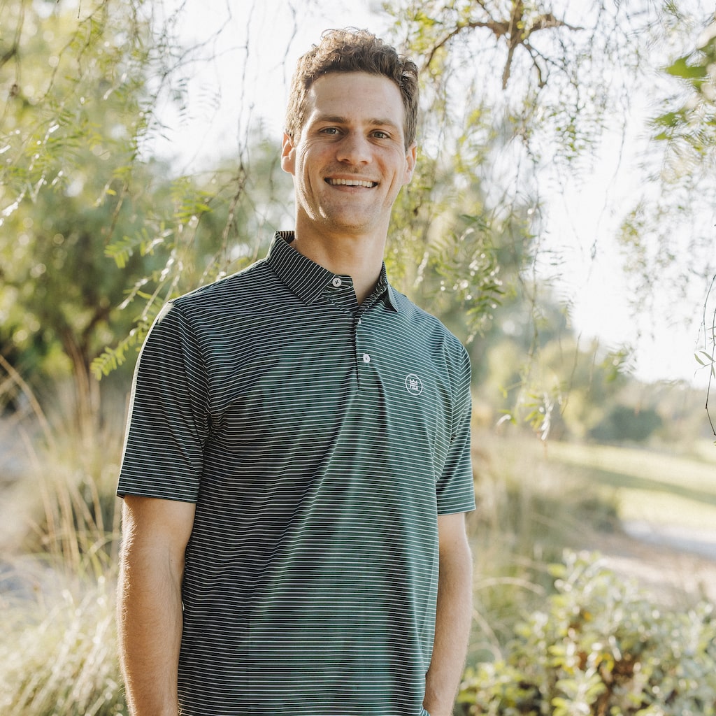 This flattering men's performance style golf polo features a hunter green color with white stripes and a breathable, flexible-fit fabric.