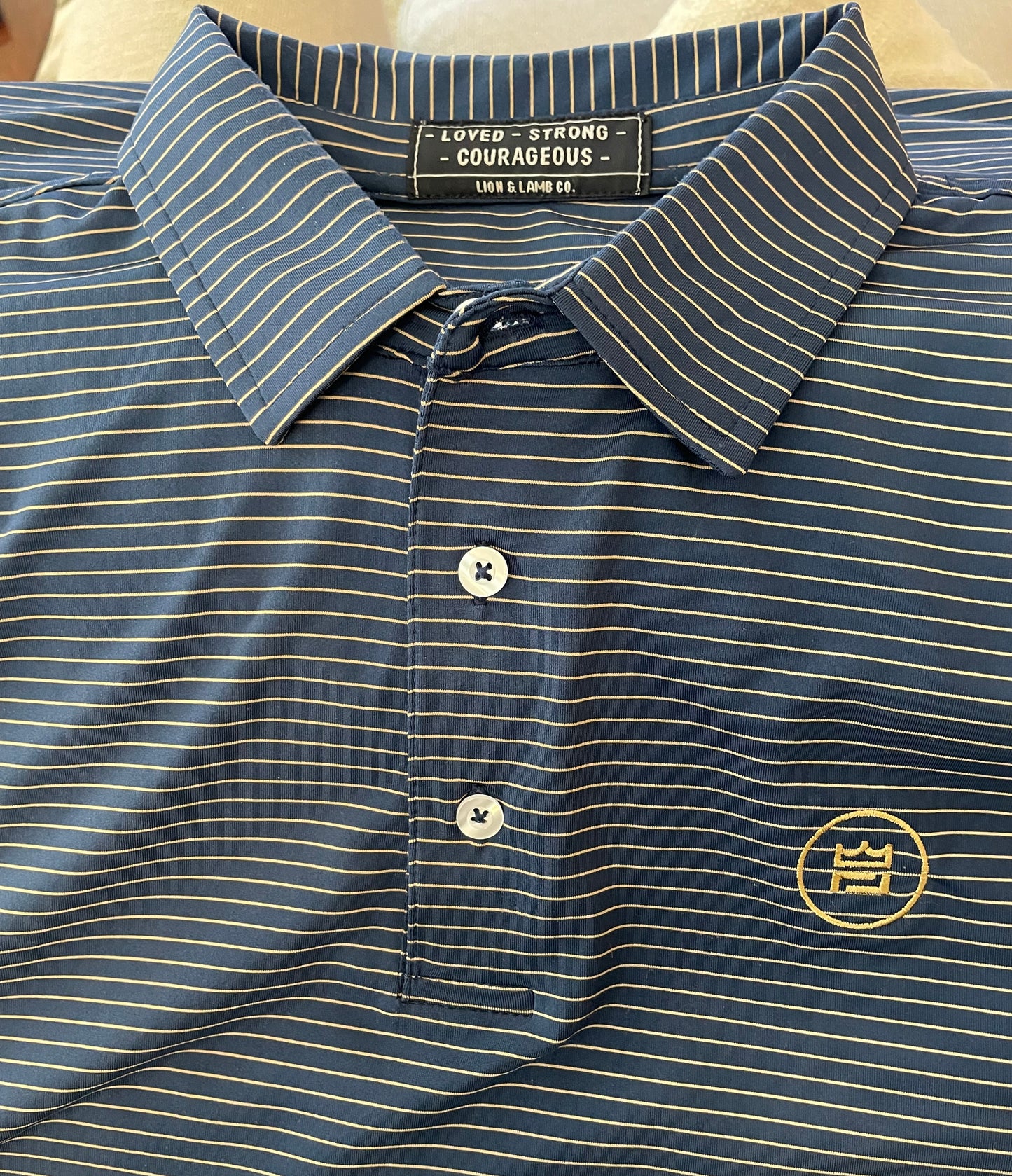This flattering men's performance style golf polo features a deep navy color with camel colored stripes and a breathable, flexible-fit fabric.