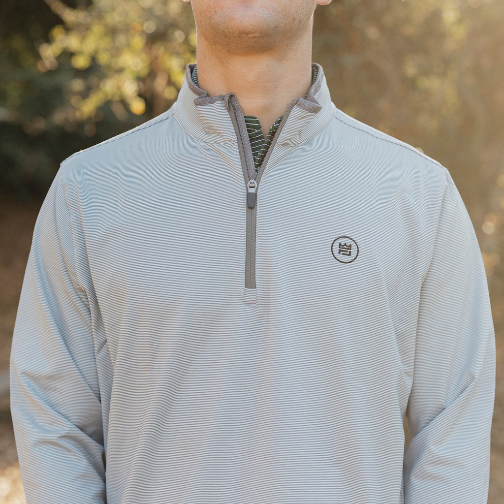 The Grey Quarter Zip outerwear piece features a subtle stripe pattern that flatters all and pairs with your favorite golf polo. It's breathability and stretch properties provide optimal mobility from the office to a night out.
