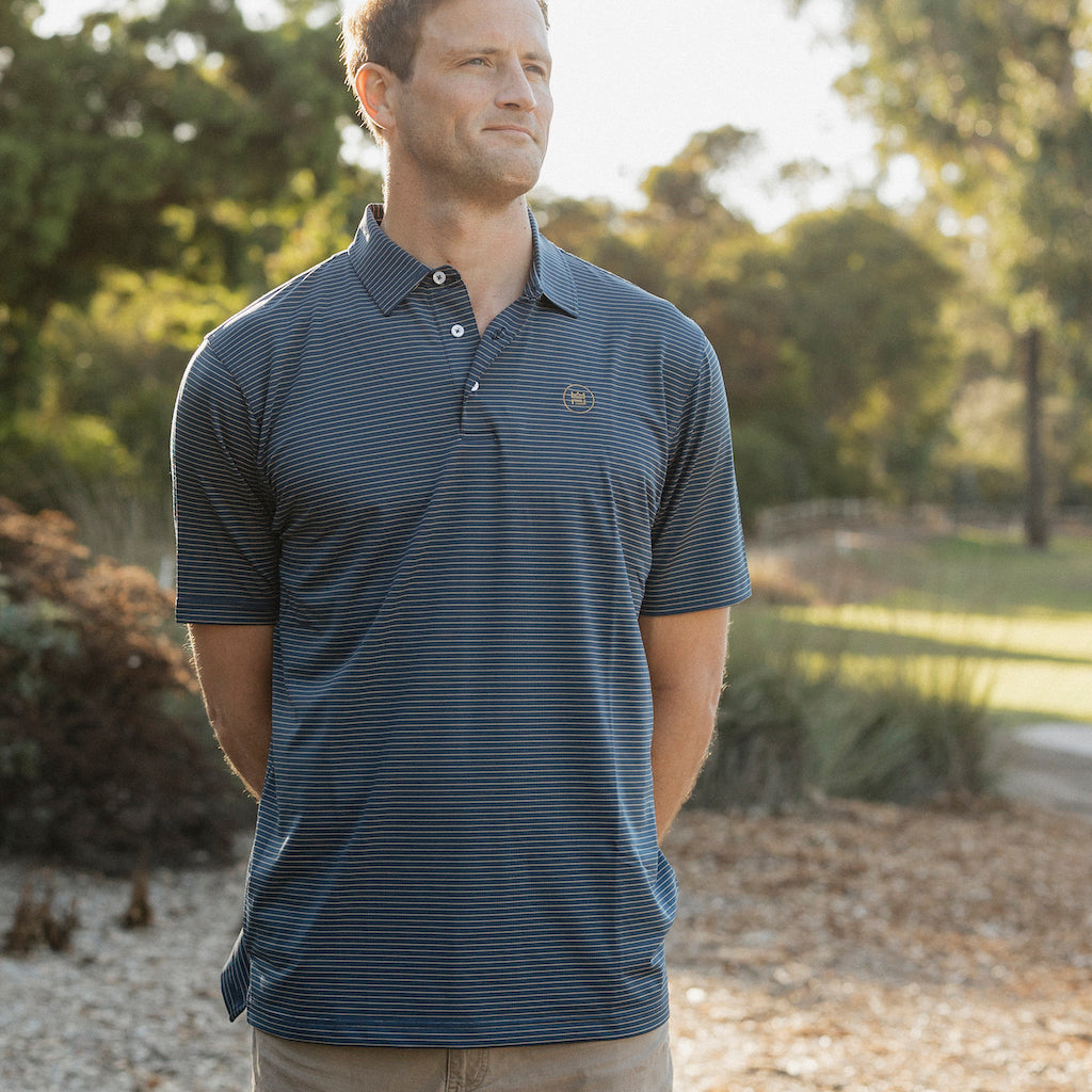 This flattering men's performance style golf polo features a deep navy color with camel colored stripes and a breathable, flexible-fit fabric.