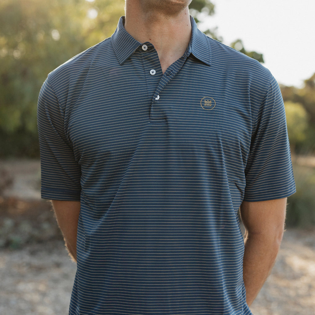 This flattering men's performance style golf polo features a deep navy color with camel colored stripes and a breathable, flexible-fit fabric.